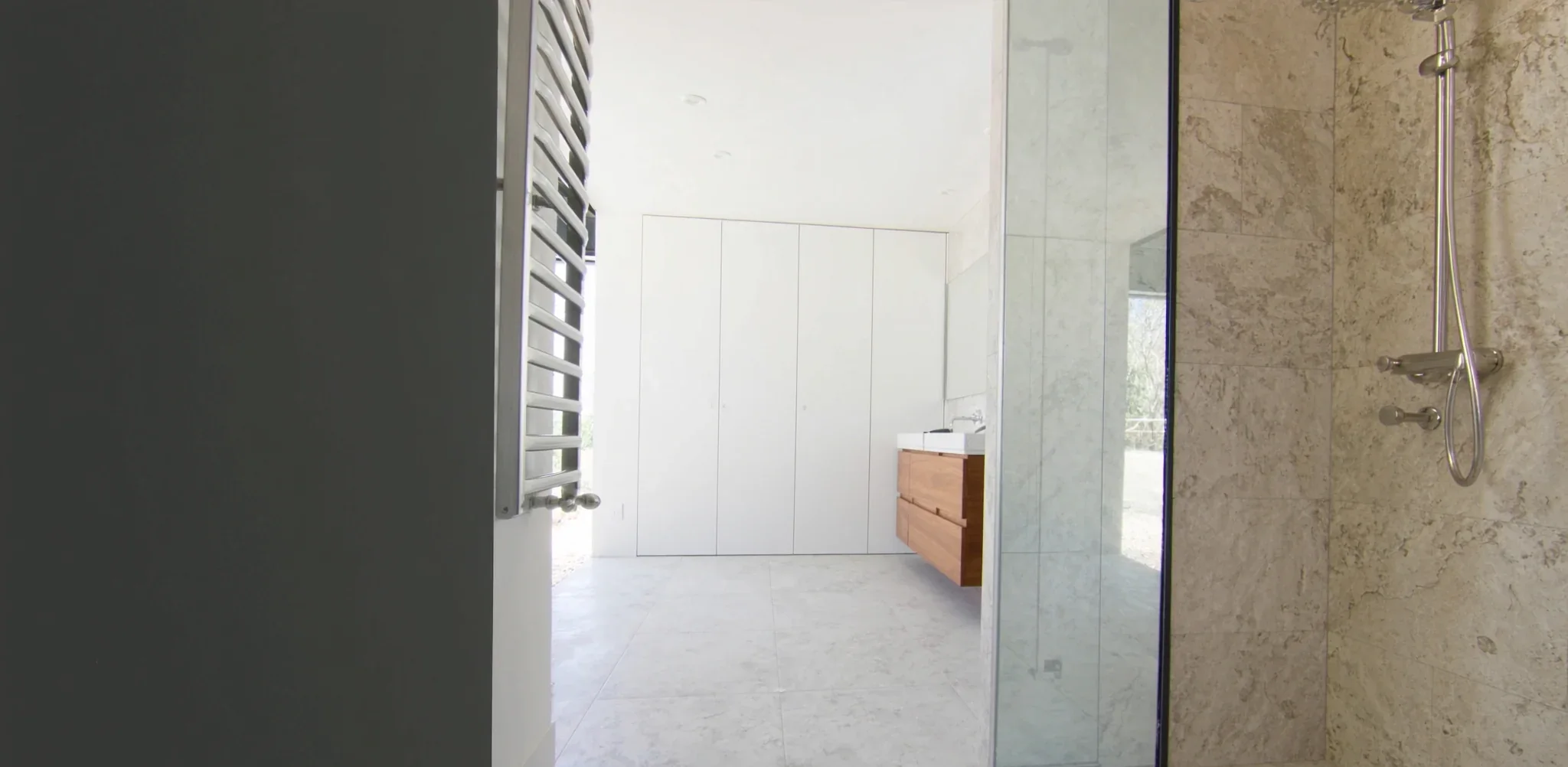 Renovated bathroom with stone-look wall tiles, walk-in shower and wall-hung timber vanity